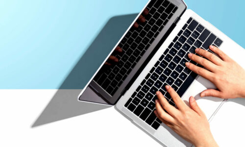 Zwei Hände tippen auf einem Laptop